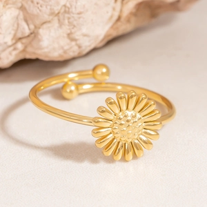 Detail of adjustable gold sunflower ring with polished finish on a stone background