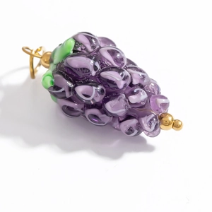 Détail d'un pendentif en verre en forme de raisin violet avec feuille verte et boucle