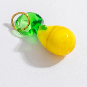 Détail d'un pendentif en verre en forme de fruit jaune et vert avec un anneau doré