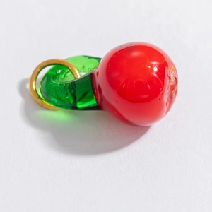 Détail d'un pendentif cerise en verre artisanal avec anneau doré pour création de bijoux
