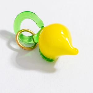 Vue macro d'un pendentif citron en verre jaune avec boucle verte et anneau doré