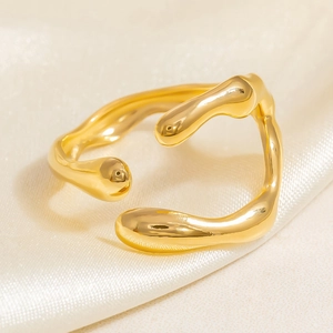 Detailansicht eines unregelmäßigen goldfarbenen Rings auf weißem Seidenhintergrund