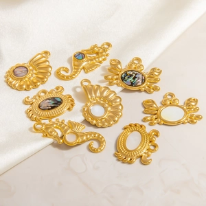 Makro-Detail von goldenen Seepferdchen- und Krabbenanhängern mit Perlmutt-Inlays