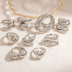 Polished silver irregular heart rings and liquid metal style bands on marble base