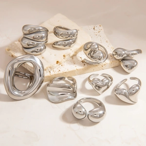 Macro shot of liquid metal style irregular heart rings on a beige marble stone pedestal