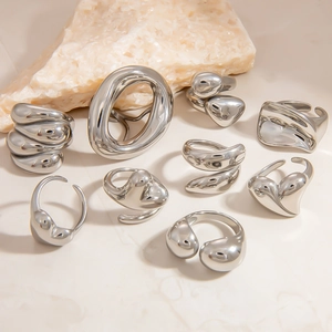 Detailed collection of irregular silver stainless steel rings on a white stone background