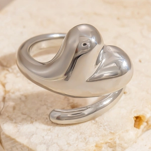 Macro shot of polished silver heart-shaped adjustable ring on a textured stone surface