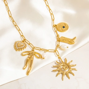 Dettaglio della collana a catena dorata con ciondoli a forma di sole, fiocco e perle