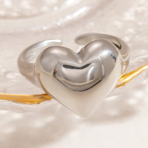 Macro shot of polished silver heart ring with adjustable open band on glass tray