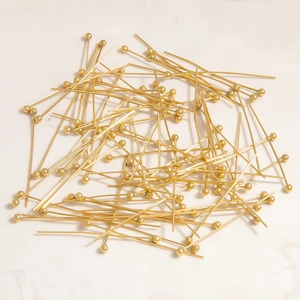 Macro shot of gold plated ball head pins for DIY jewelry making on stone background