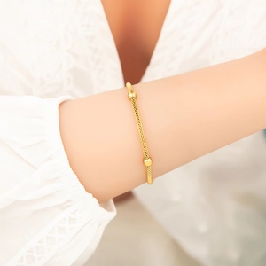 Detailansicht eines Goldgitter-Armbands mit Perlenakzenten am Handgelenk einer Frau