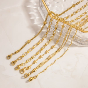 Detail von sechs 18K vergoldeten Edelstahlarmbändern mit Karabinern auf Glasdekor