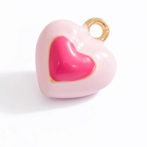Macro detail of a pink heart-shaped enamel pendant with a gold ring clasp for DIY jewelry