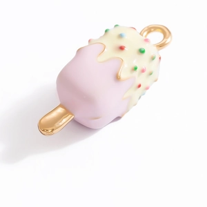 Detailed view of ice cream charm with pink enamel finish and colorful sprinkles on gold alloy