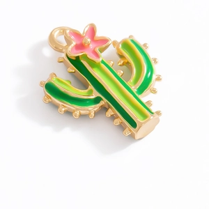 Macro detail of a green cactus charm with pink flower and golden finish for DIY jewelry