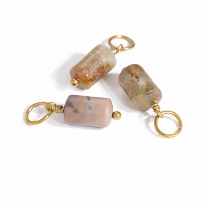 Detailed macro view of three cylindrical natural stone pendants with gold metal rings