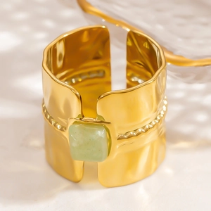 Macro detail of gold-plated hammered ring with square green gemstone and beaded edges