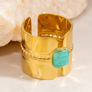 Detail of wide gold textured open ring with green square gemstone and beaded pattern