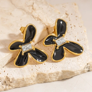 Nahaufnahme von Blumen-Ohrsteckern mit schwarzer Emaille und Zirkon auf einem Stein