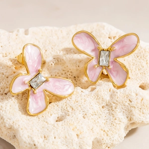 Detailansicht der rosa Schmetterling Ohrringe mit Goldbeschichtung auf weißem Korallenstein