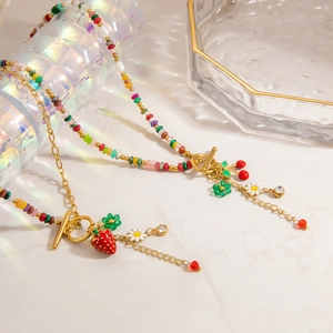 Close-up of beaded necklace with strawberry, daisy charms and a golden toggle clasp