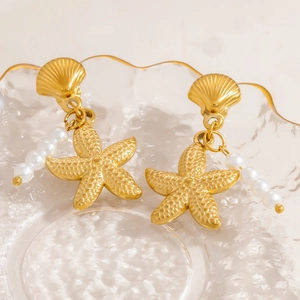 Boucles d'oreilles étoile de mer dorées avec perles sur plateau verre, bijou élégant de plage