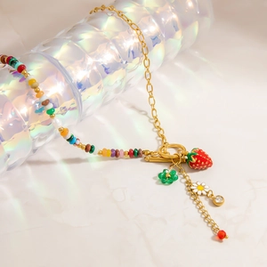 Detail of beaded necklace with strawberry, daisy charms and a golden OT toggle clasp