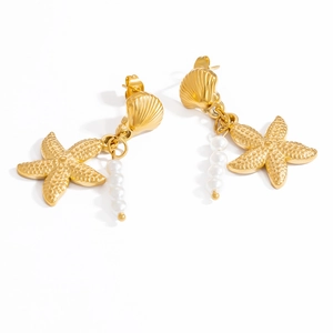 Détail de boucles d'oreilles étoile de mer dorées avec clous coquillage et perles