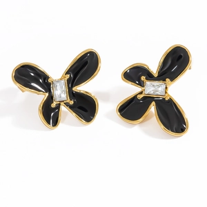 Makroaufnahme von 18k vergoldeten Blumenohrsteckern mit schwarzer Emaille und Zirkon
