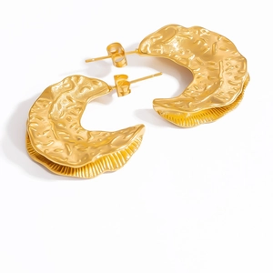 Macro view of gold-plated stainless steel earrings with molten lava textured finish