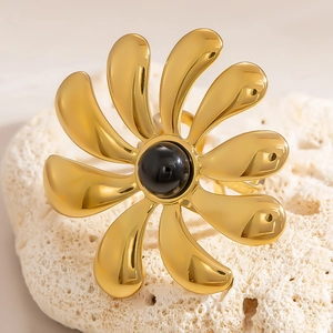 Macro detail of 18k gold plated flower ring with black gemstone on coral stone