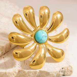 Macro shot of 18k gold plated flower ring with a round turquoise stone on stone background