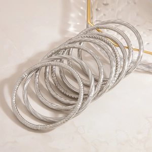 Detail of silver twisted stainless steel bangles with textured spiral engraving