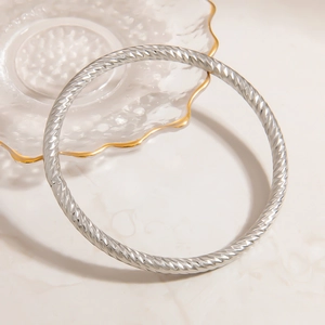 Macro shot of silver stainless steel bangle with detailed diamond-cut textured patterns
