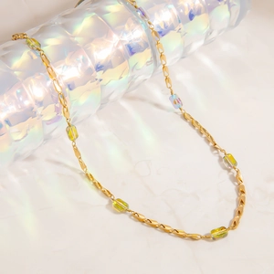 Detail of 18K gold-plated chain with iridescent rectangular glass beads on marble