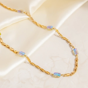 Detailed shot of 18K gold-plated necklace with aurora crystals on silk background