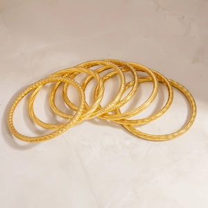 Close-up of seven 18K gold plated stainless steel twisted bangles with spiral texture