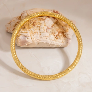 Detailed macro view of 18K gold plated stainless steel twisted rope bracelet with texture