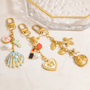 Golden pearl bag charms with starfish and seashell pendants on marble tray