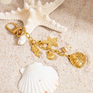 Golden ocean theme keychain with starfish, seashell pendants and pearls on white sand