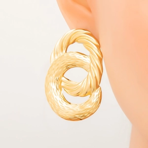 Close-up of golden geometric earrings featuring interlocking hammered and twisted metal rings