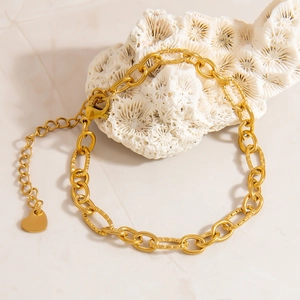 Dettaglio del bracciale a catena placcato oro 18k con ciondolo a cuore su corallo bianco
