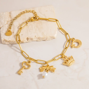 Close-up of gold paperclip chain bracelet with heart, crown, and pearl charms