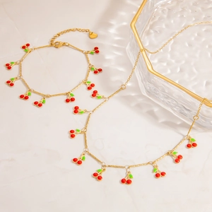 Detail view of gold stainless steel necklace and bracelet set with cherry charms
