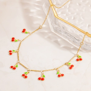 Detailed shot of golden spiral chain necklace with multiple red cherry pendants