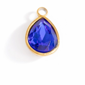 Macro detail of tear-drop dark blue crystal pendant with golden plated metal frame
