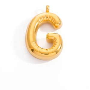 Macro detail of gold G-shaped balloon letter pendant with glossy metallic finish