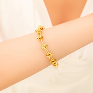 Bracelet noeud en acier inoxydable doré 18K sur poignet féminin avec lumière chaude