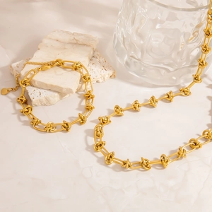 Détail du parure collier et bracelet en acier inoxydable doré 18 carats avec motif de nœud