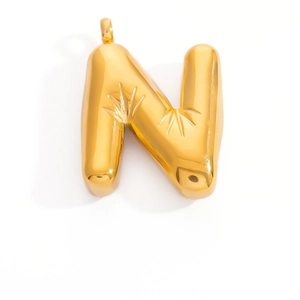 Macro shot of 3D gold-plated letter N pendant with starburst engraving and polished finish